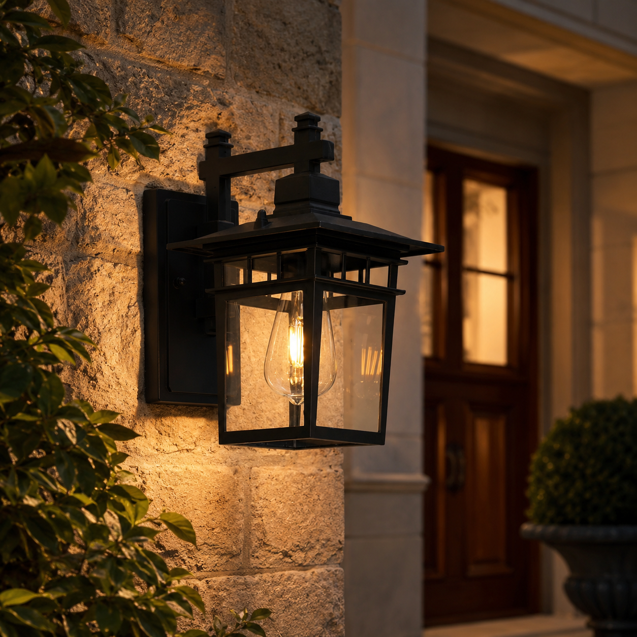 Black outdoor porch wall lantern mounted on a stone exterior wall with warm ambient glow