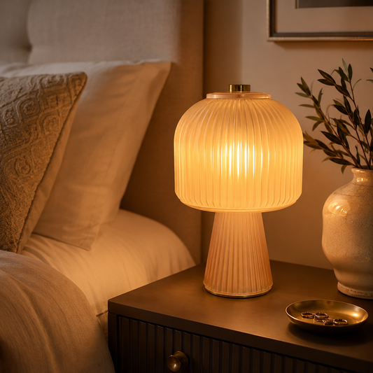 Stained glass table lamp glowing warmly on a bedside table in a modern bedroom.